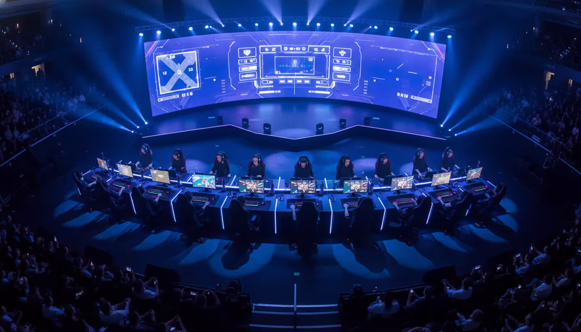Professional esports tournament stage with players sitting at gaming monitors under blue and purple neon lighting, large screen in the background showing abstract competitive game interface